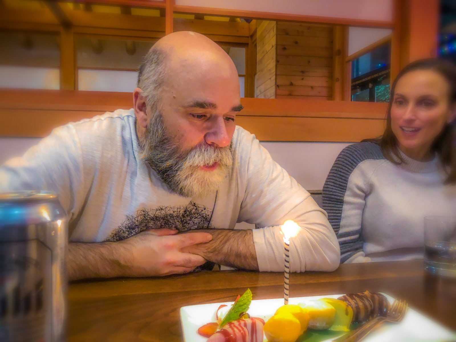 Tuss leaning toward a birthday candle at a restaurant